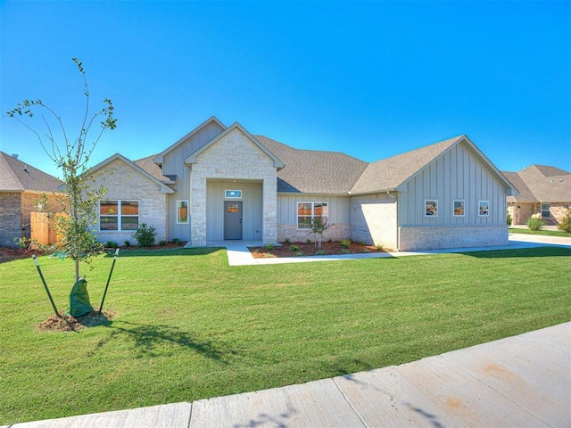 view of front of home featuring stone siding, board and batten siding, a shingled roof, and a front yard