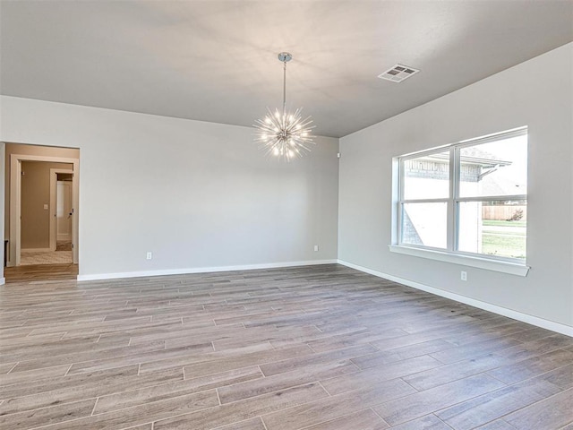 spare room with visible vents, baseboards, an inviting chandelier, and light wood finished floors