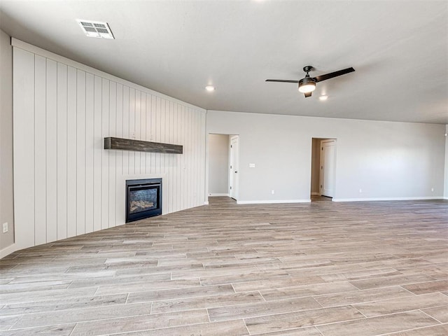 unfurnished living room featuring a ceiling fan, visible vents, baseboards, a fireplace, and light wood-style floors