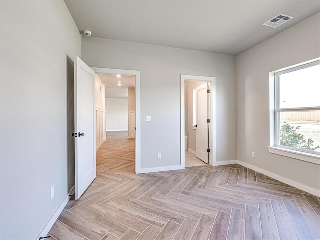 unfurnished bedroom with visible vents, baseboards, and connected bathroom