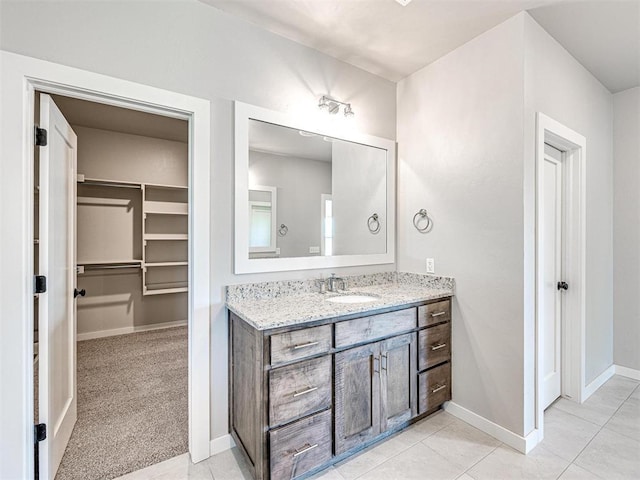 bathroom featuring tile patterned flooring, a spacious closet, vanity, and baseboards