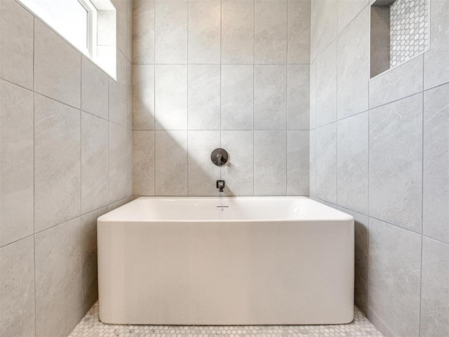 full bath featuring a soaking tub and tile walls