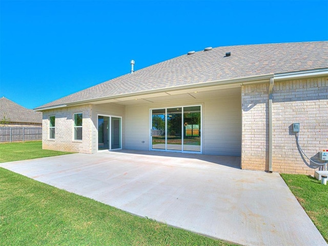 rear view of property featuring a patio area, brick siding, a lawn, and fence