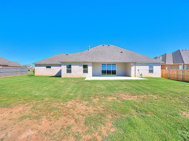 rear view of property with a yard, a patio, brick siding, and a fenced backyard