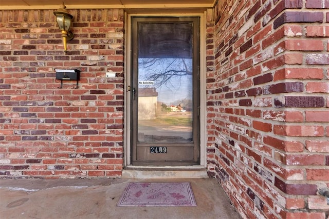 doorway to property featuring brick siding