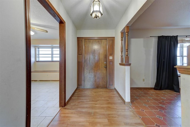 entrance foyer featuring light wood-type flooring, plenty of natural light, a textured ceiling, and baseboards