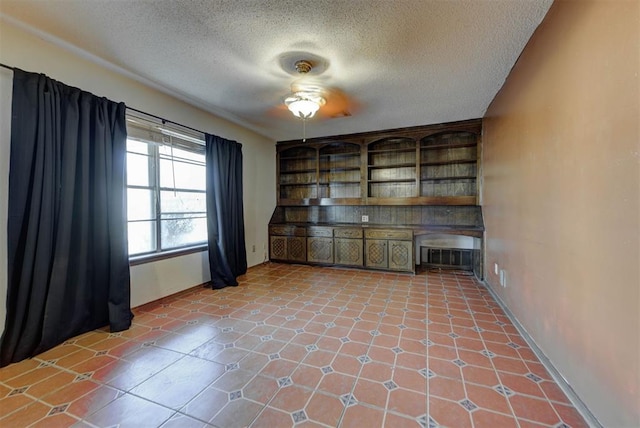 spare room with light tile patterned floors, baseboards, and a textured ceiling