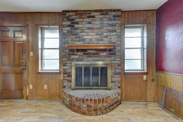 living area with a wealth of natural light, wooden walls, and wood finished floors