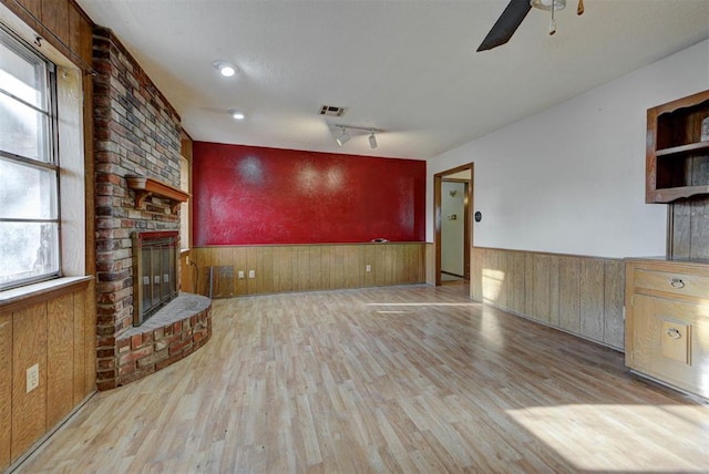 unfurnished living room featuring visible vents, wood finished floors, and wainscoting