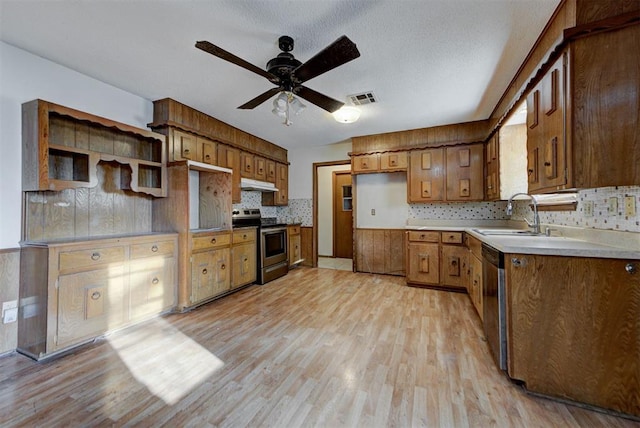 kitchen featuring visible vents, under cabinet range hood, light wood-style flooring, stainless steel appliances, and a sink