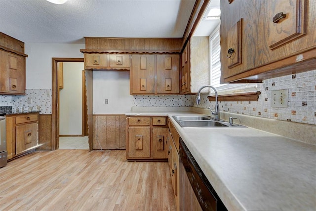 kitchen with light wood-style flooring, a sink, light countertops, dishwasher, and brown cabinets