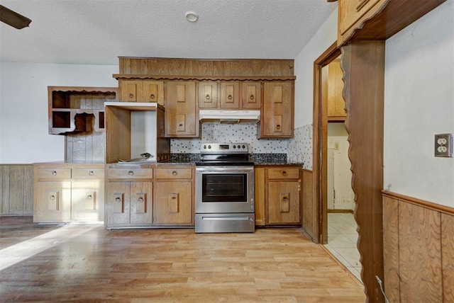 kitchen with under cabinet range hood, dark countertops, a textured ceiling, stainless steel electric range, and light wood finished floors