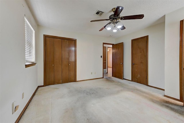 unfurnished bedroom featuring visible vents, a textured ceiling, carpet floors, baseboards, and ceiling fan