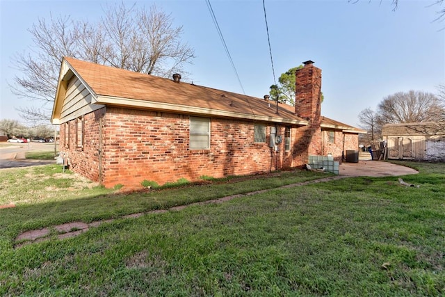 back of house with brick siding, a lawn, a chimney, and a patio area