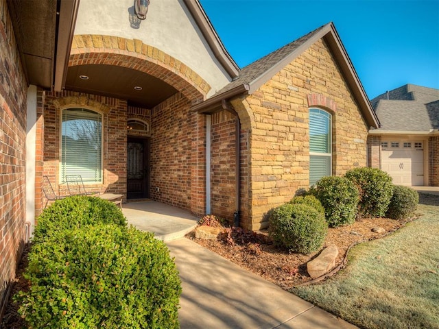 doorway to property featuring brick siding and a garage