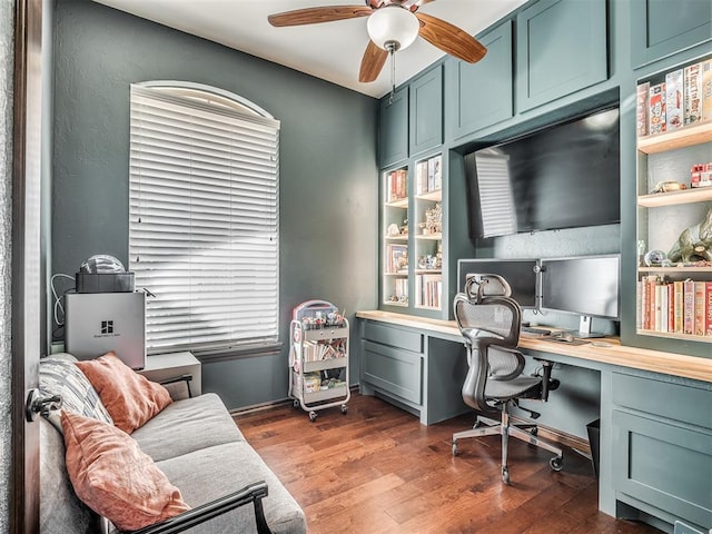 office area featuring ceiling fan, wood finished floors, and built in study area