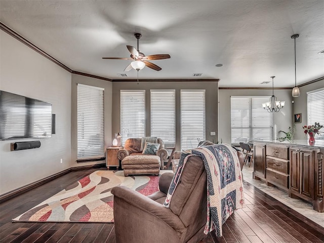 living room with ceiling fan with notable chandelier, wood finished floors, visible vents, and ornamental molding