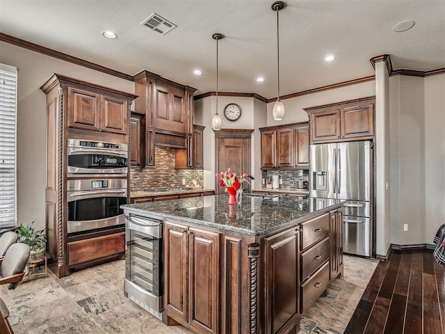 kitchen with visible vents, beverage cooler, a center island with sink, stainless steel appliances, and dark stone counters