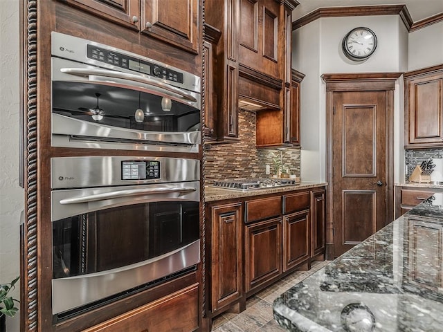 kitchen featuring dark stone counters, crown molding, tasteful backsplash, and appliances with stainless steel finishes