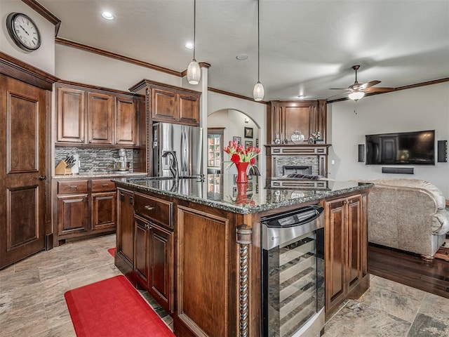 kitchen with an island with sink, stainless steel refrigerator with ice dispenser, tasteful backsplash, dark stone counters, and wine cooler