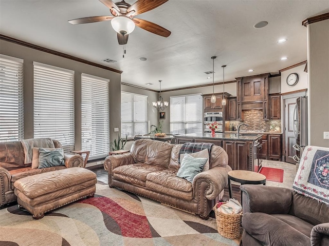 living room featuring recessed lighting, ceiling fan with notable chandelier, visible vents, and ornamental molding