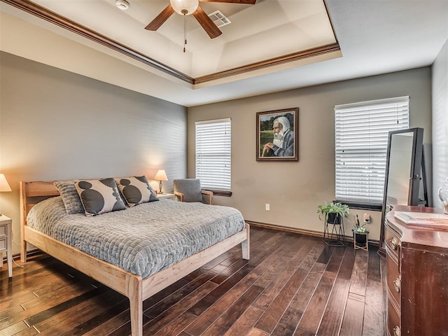 bedroom featuring visible vents, dark wood-type flooring, a ceiling fan, a tray ceiling, and baseboards