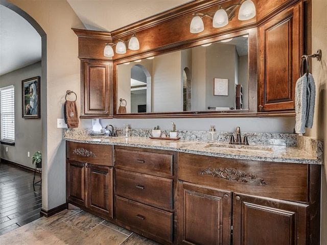 full bathroom with double vanity, baseboards, and a sink