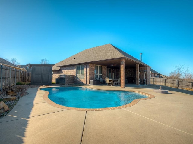 view of swimming pool with a patio, a fenced in pool, a fenced backyard, an outdoor structure, and a storage unit