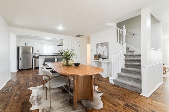 dining space featuring dark wood-style floors, visible vents, stairway, and baseboards