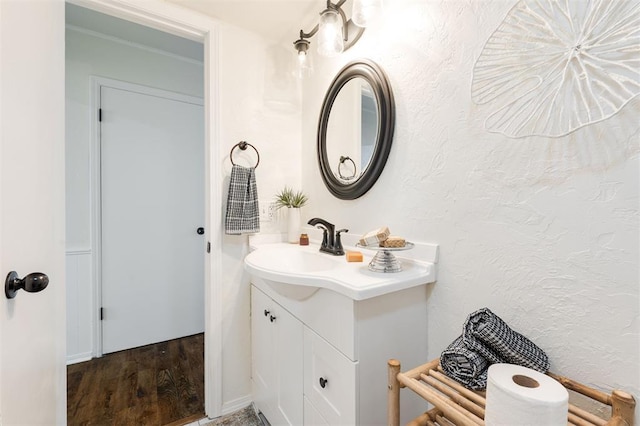 bathroom with wood finished floors, vanity, and a textured wall