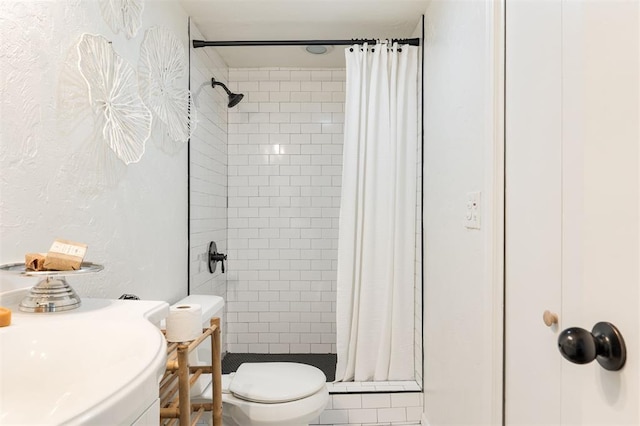 full bathroom featuring toilet, a textured wall, and a stall shower