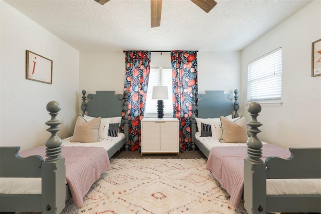 bedroom featuring multiple windows, a textured ceiling, light colored carpet, and ceiling fan