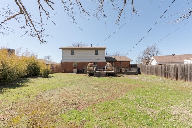 back of property with a deck, a lawn, and a fenced backyard