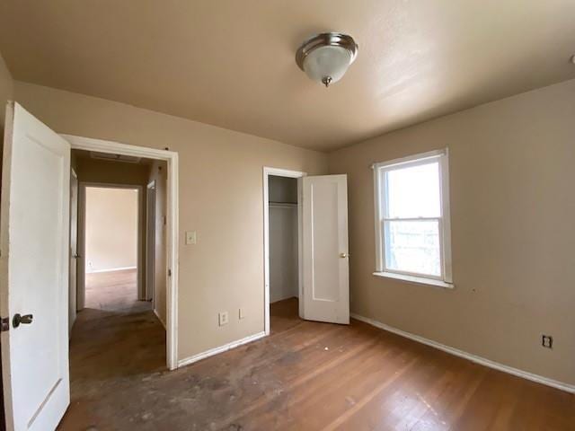 unfurnished bedroom featuring a closet, baseboards, and wood finished floors