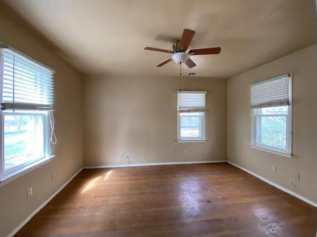 spare room featuring a wealth of natural light, baseboards, a ceiling fan, and wood finished floors