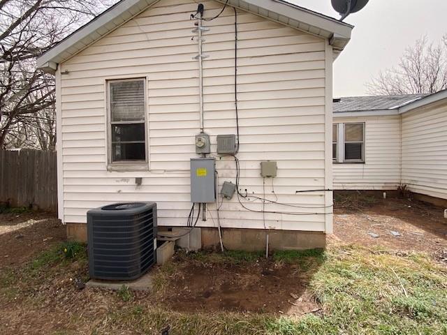 view of side of property with central air condition unit and fence