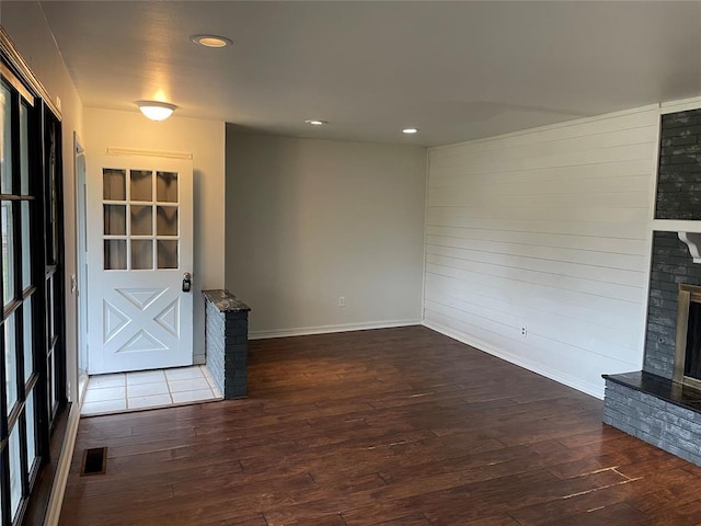 unfurnished living room featuring recessed lighting, visible vents, a fireplace with raised hearth, and dark wood-style floors