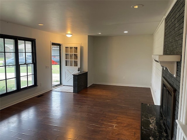 unfurnished living room featuring dark wood finished floors, recessed lighting, baseboards, and a large fireplace