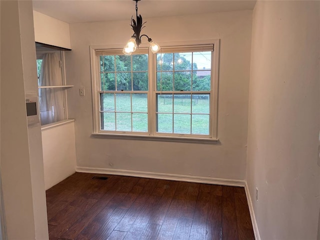 unfurnished dining area featuring a chandelier, baseboards, visible vents, and dark wood finished floors