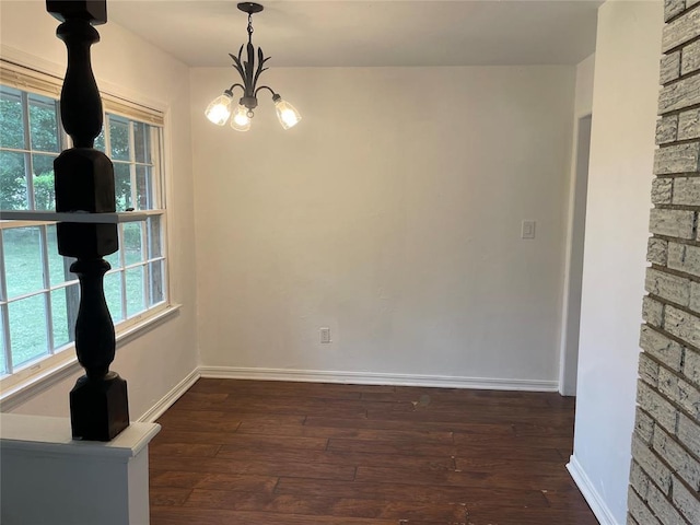 unfurnished dining area featuring baseboards, a notable chandelier, and dark wood-style flooring