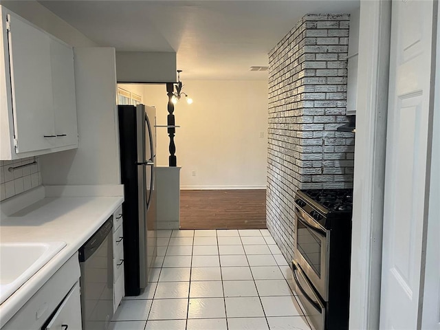 kitchen featuring light countertops, stainless steel appliances, light tile patterned flooring, white cabinetry, and a sink