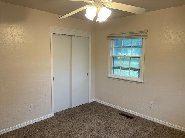 unfurnished bedroom featuring a closet, carpet flooring, visible vents, and a textured wall