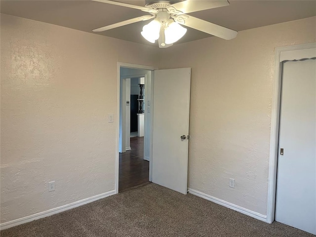 unfurnished bedroom with a textured wall, baseboards, carpet floors, and ceiling fan