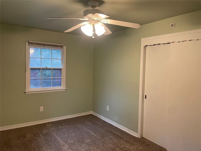 spare room featuring baseboards, ceiling fan, and dark carpet