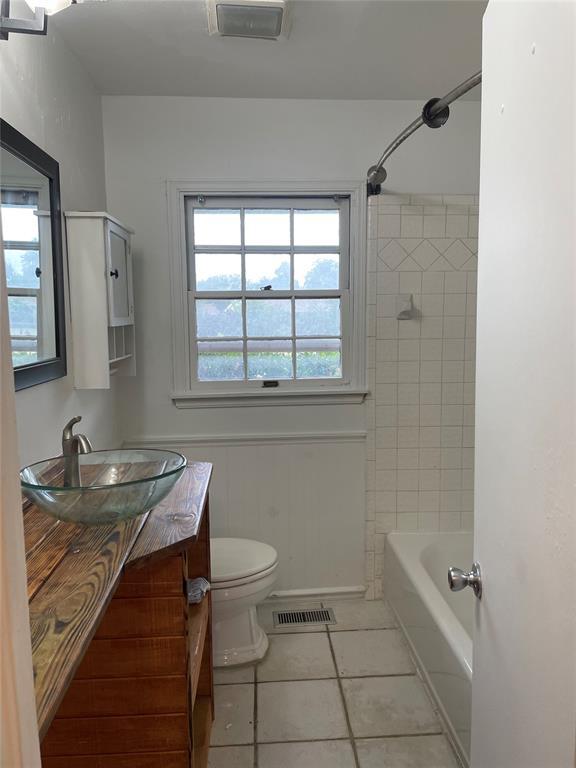 bathroom featuring visible vents, a wainscoted wall, toilet, tile patterned floors, and vanity