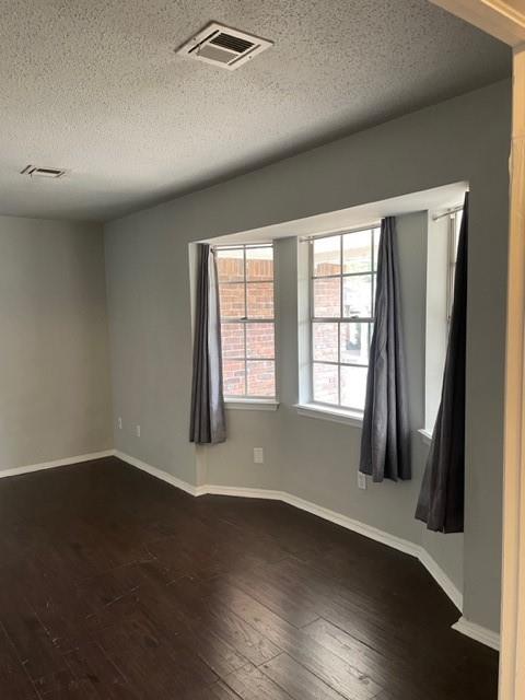 unfurnished room with visible vents, dark wood-type flooring, and baseboards