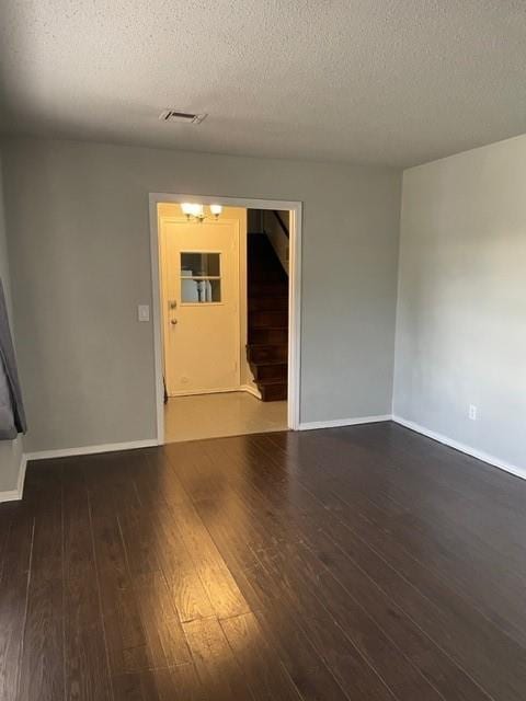 spare room with visible vents, baseboards, a textured ceiling, and hardwood / wood-style flooring