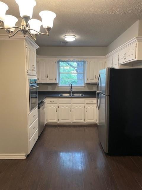 kitchen featuring dark wood-style flooring, appliances with stainless steel finishes, an inviting chandelier, and a sink