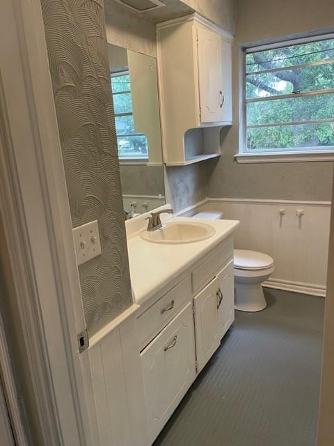 bathroom with a wainscoted wall, toilet, and vanity