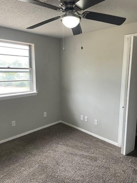 carpeted spare room featuring baseboards, a textured ceiling, and a ceiling fan